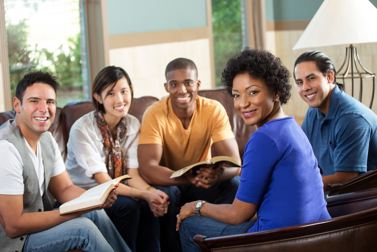 A small group sitting together in a living room with open Bibles